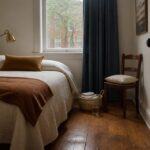 Guest bedroom with a made bed, bedside table, and open floor space